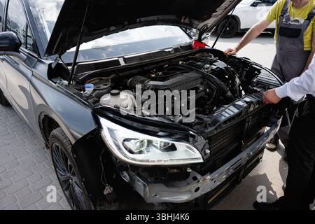 Two mechanics inspecting the engine of a vehicle with the hood open. Stock Photo