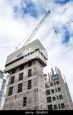 Construction site featuring high-rise buildings under development with a prominent crane and concrete service core Stock Photo