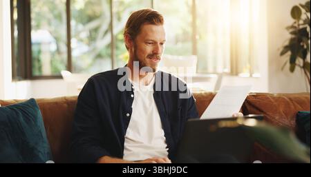 Man, paper and reading on sofa with laptop, writer and thinking for script draft in home. Person, editor and technology in living room for research Stock Photo