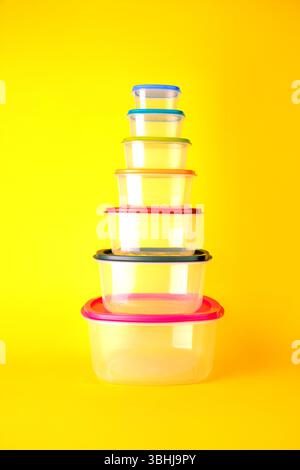 Transparent plastic containers with colorful lids stacked in a pyramid ...