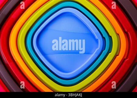 Overhead view of stacked plastic trays in vibrant rainbow colors forming a geometric pattern. Stock Photo