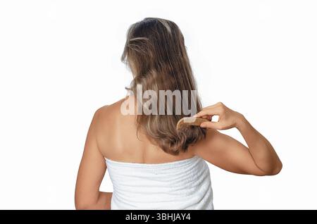 Combing woman's wavy hair after shower with wooden comb on white background. Care for healthy and clean hair Stock Photo