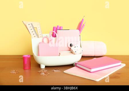 Holder with different stationery and notebooks on wooden desk Stock Photo