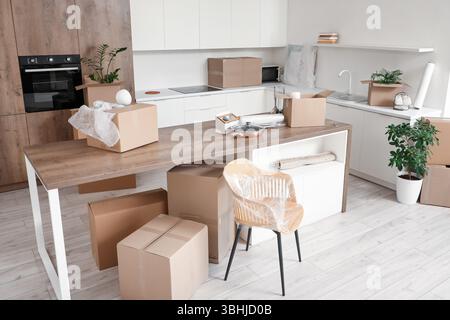 Interior of kitchen with counters, table and cardboard boxes on moving ...