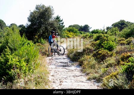 Woman tourist on a cycling trip, exploring Kamenjak peninsula in Istria, Croatia, mountain bike trails surrounded with beautiful landscape Stock Photo