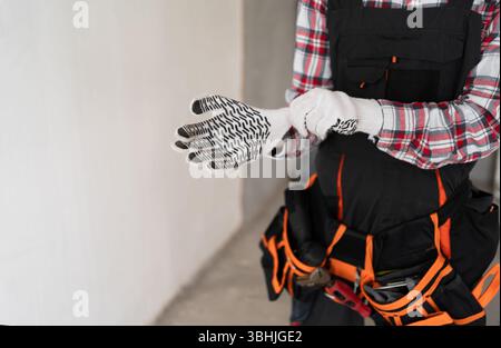 close up of builder hands putting on work gloves. Construction site and building concept Stock Photo