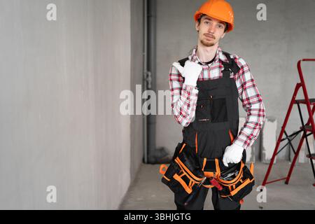 construction worker in yellow helmet pointing with thumb at space for text or advertisement standing on construction site Stock Photo