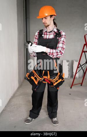 foreman or builder using smartphone searching business contact in construction site. Modern connection technology Stock Photo