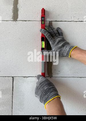 Bricklayer Using a Spirit Level to Check New Red Brick Wall Outdoor. Bricklaying Basics Masonry Techniques. Stock Photo