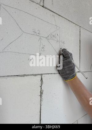 DIY construction. A man's hands make marks on a wall with a construction pencil. Construction marks on a block wall. Stock Photo