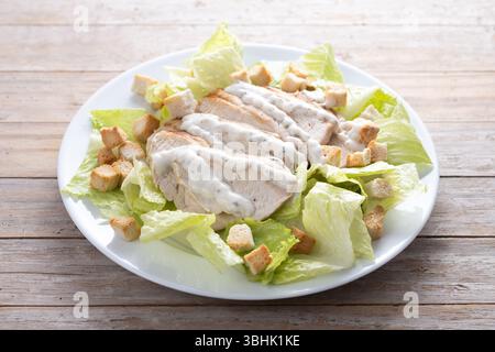 Crunchy Caesar salad with chicken on wooden table Stock Photo