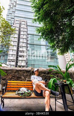 Man sitting and relaxing with pet dogs amid high rise buildings landscape, in mid levels, Hong Kong, SAR, China Stock Photo