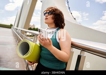 A young, pretty woman in activewear is outdoors, enjoying her workout and soaking up the sun. Stock Photo
