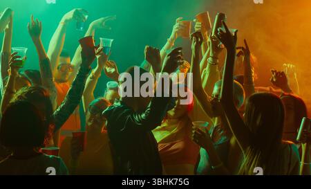 Vibrant party scene with people dancing and celebrating under colorful lights. Stock Photo