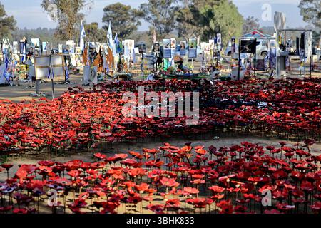 Row of red ceramic poppies fill the Re’im Forest October 7 Memorial beneath portrait sign honoring lives lost in a vivid sea of collective remembrance Stock Photo