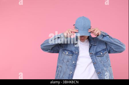 Young man wearing stylish denim baseball hat on pink background, space for text Stock Photo