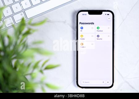 Poznan, Poland - June 10, 2025: New iOS 26 Liquid Glass smartphone on a white desk, displaying a modern password manager for enhanced digital security Stock Photo