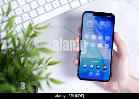 Poznan, Poland - June 10, 2025: Close-up of a hand interacting with a new smartphone, displaying iOS 26 featuring Liquid Glass design with customizabl Stock Photo