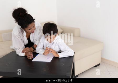 Mother assisting her son with homework, creating a positive learning environment at home Stock Photo