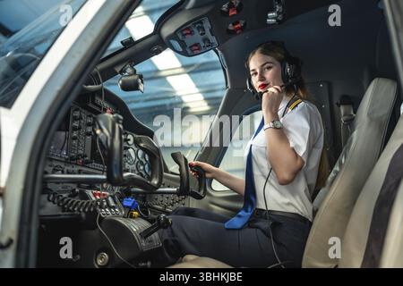 Confident female pilot preparing for takeoff, sitting in the cockpit of a small airplane, adjusting her headset Stock Photo