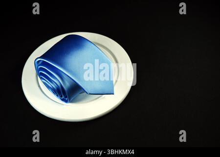 Rolled blue tie isolated on black background closeup view Stock Photo
