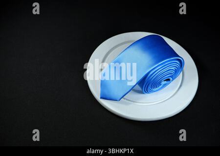Rolled blue tie isolated on black background closeup view Stock Photo