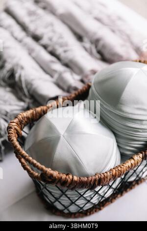 Soft silver hats neatly stored in a wicker basket, accompanied by plush blankets, create a warm indoor ambiance. Stock Photo