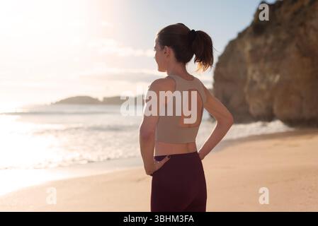 Fit Woman Standing on the Shoreline During Beautiful Beach Sunrise Stock Photo