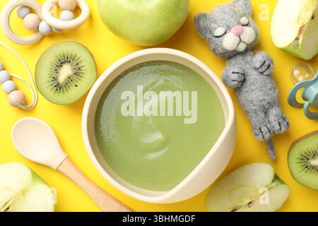 Baby food. Tasty puree in bowls, different ingredients and toys on yellow background, flat lay Stock Photo
