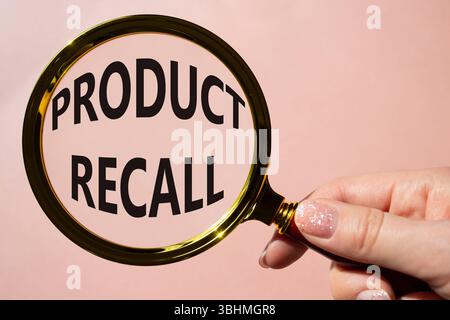 Product recall symbol. Concept words Product recall on magnifying glass. Beautiful pink background. Businessman hand. Business and Product recall conc Stock Photo