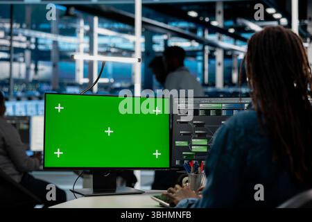 Engineer working on isolated screen desktop PC in data center housing storage infrastructure. IT professional using chroma key computer display in server hub workspace filled with networking tech Stock Photo
