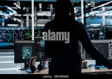 Data center engineer uses AI visualization tool on laptop to oversee automated repetitive tasks. Worker adapting server systems based on data analytics graphs using notebook device Stock Photo