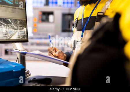 Closeup of professional engineer controlling industrial automation system. Smart manufacturing plant integrates digital technology, robotic arms and automated conveyor belts for streamlined production Stock Photo