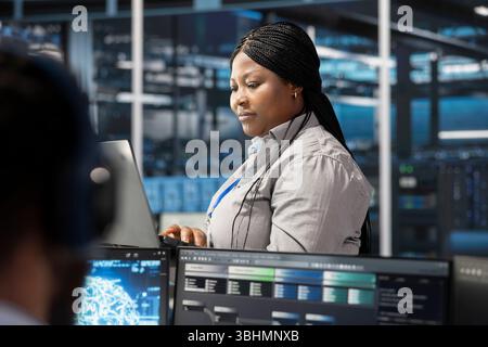 Data center software developer using artificial intelligence neural networks tech. African american server farm employee using AI programming language on computer, configuring specialized hardware Stock Photo