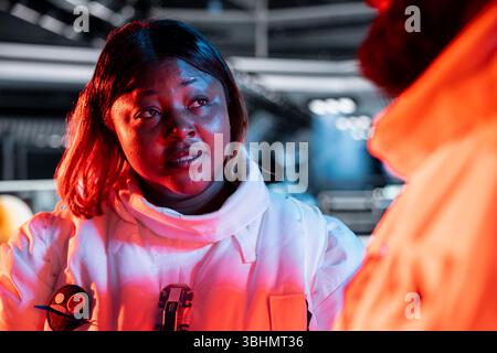 Team of spaceship engineers following danger protocol to fix security breach causing overload warning. Space station coworkers repairing critical systems after asteroids debris impact Stock Photo