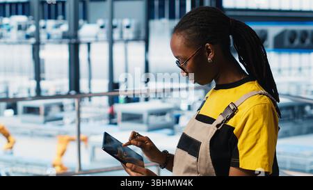 Smart factory engineer implements automated workflows using artificial intelligence tech, computerizing manual operations. Woman integrates sensors into production using AI technology, camera A Stock Photo