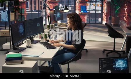Woman IT developer using pc setup for artificial intelligence cloud computing through self learning algorithms. Agency system engineer works with AI deep neural networks on desktop. Camera A. Stock Photo