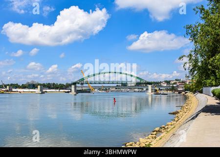 Workers and machines dismantle the Old Sava Bridge in Belgrade with Kalemegdan and New Belgrade skyline in background. Stock Photo