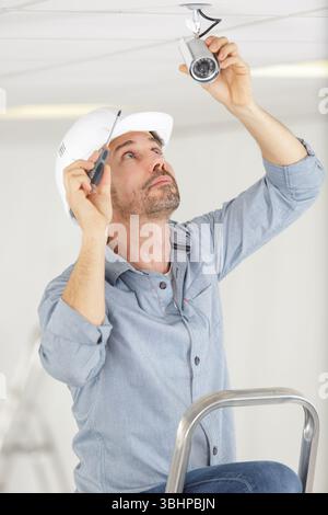 man installs surveillance ip camera for home security Stock Photo