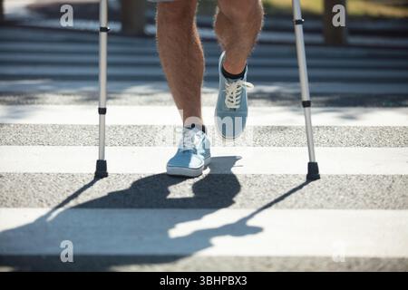 man with crutchen crossing street Stock Photo