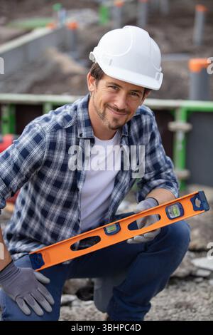 young handyman using spirit level outdoors Stock Photo