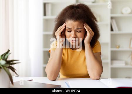 Stressed Black Female Freelancer Having Headache While Working At Desk In Home Stock Photo