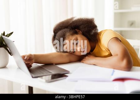 Exhausted Black Female Student Sleeping At Desk With Workbooks And Laptop Stock Photo