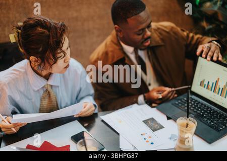 Collaborative business strategy session between two diverse people analyzing data and discussing plans Stock Photo