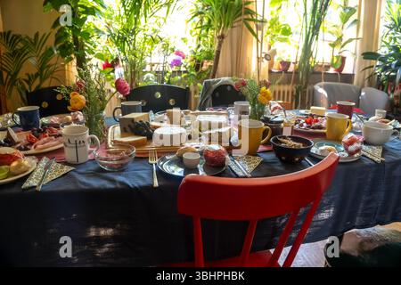 Large dining table, fully set with cheese, sausage and more delicacies for a meal with family or friends in a living room, selected focus, narrow dept Stock Photo