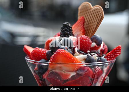 Ice cream sundae with fruits, blueberries and strawberries in a street cafe, copy space, selected focus, narrow depth of field Stock Photo