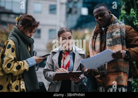 Multiracial team strategizing and collaborating outdoors with documents and mobile devices Stock Photo