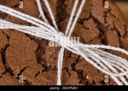 sweet chocolate biscuits on the kitchen table, chocolate biscuits with real cocoa and sesame , cookies are tied with rope Stock Photo
