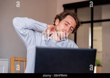 Seated man stretching during work to relieve muscle stiffness Stock Photo