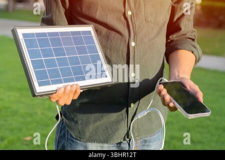 Cropped view of eldery man with a mobile phone standing with solar panels at outdoor. Clean energy concept. Stock Photo